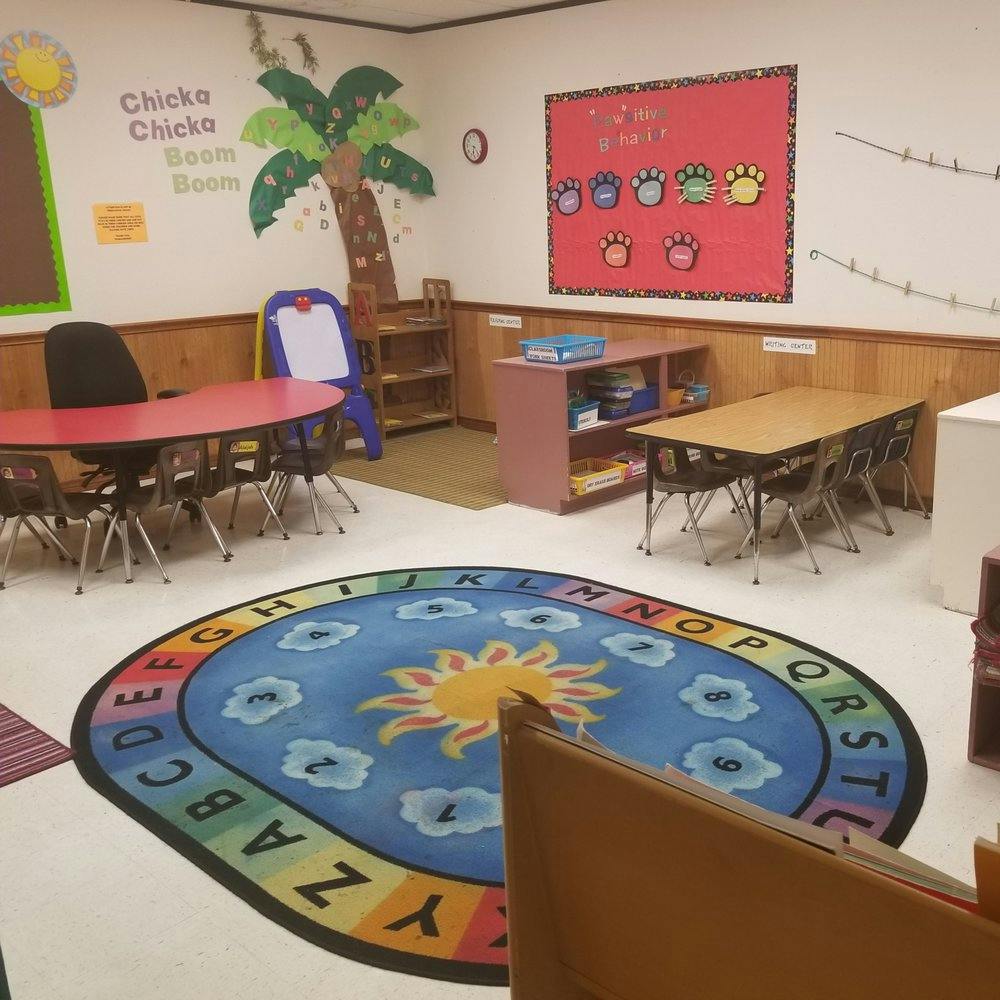 Classroom with tables, chairs, and an alphabet rug