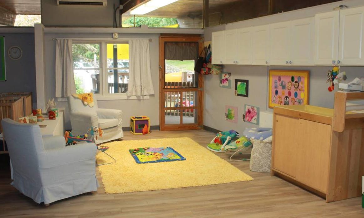 Playroom with yellow rug, two chairs, and changing table