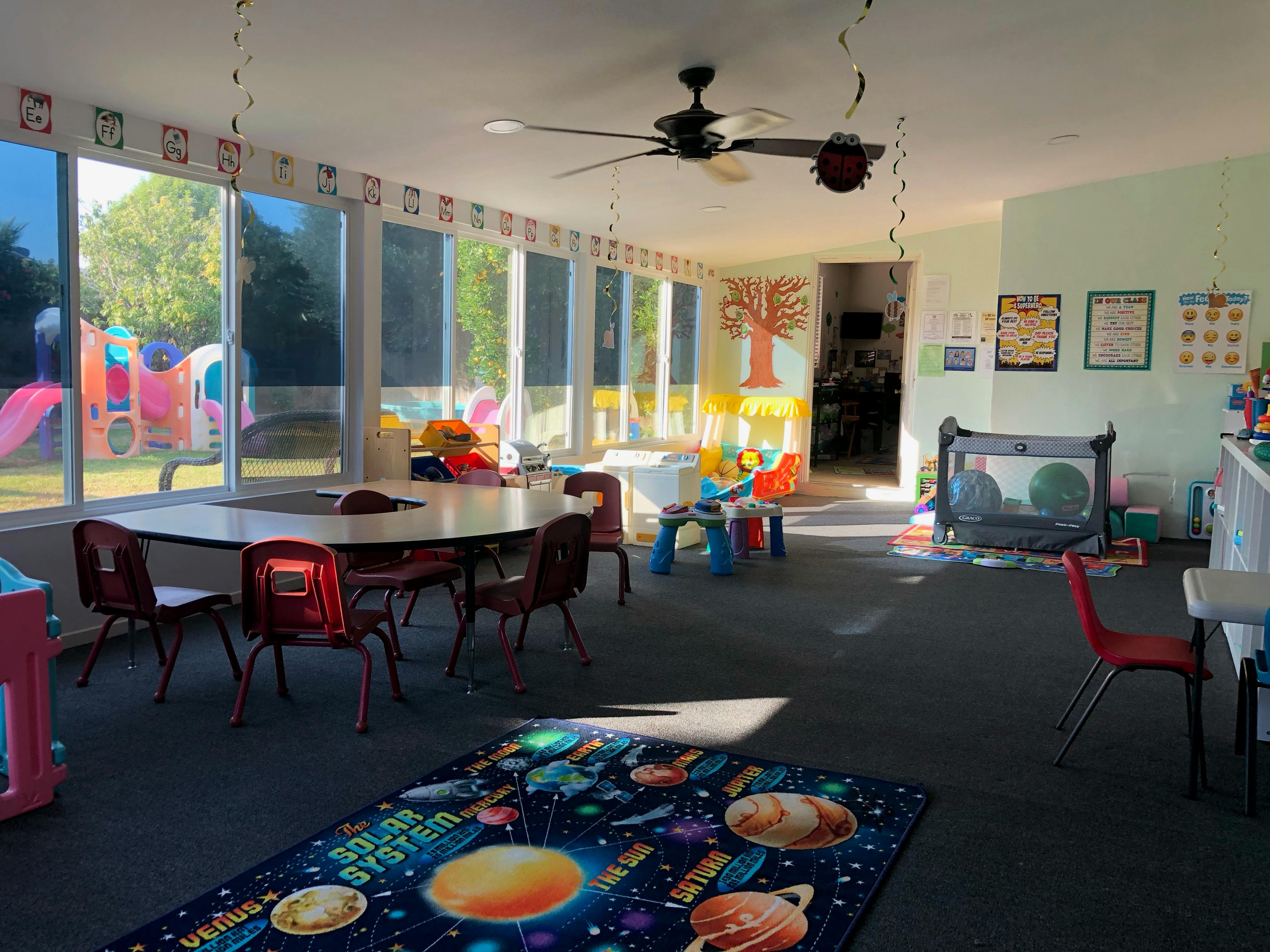 Playroom with tables, chairs, and a space-themed rug