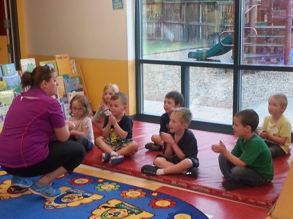 Adult and children sitting on floor in classroom