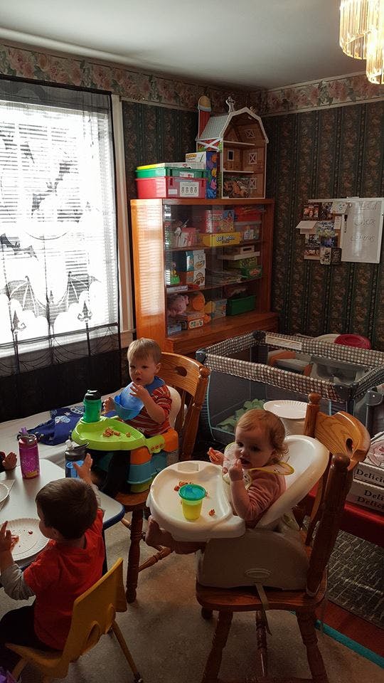 Three children sitting at a table, two in high chairs