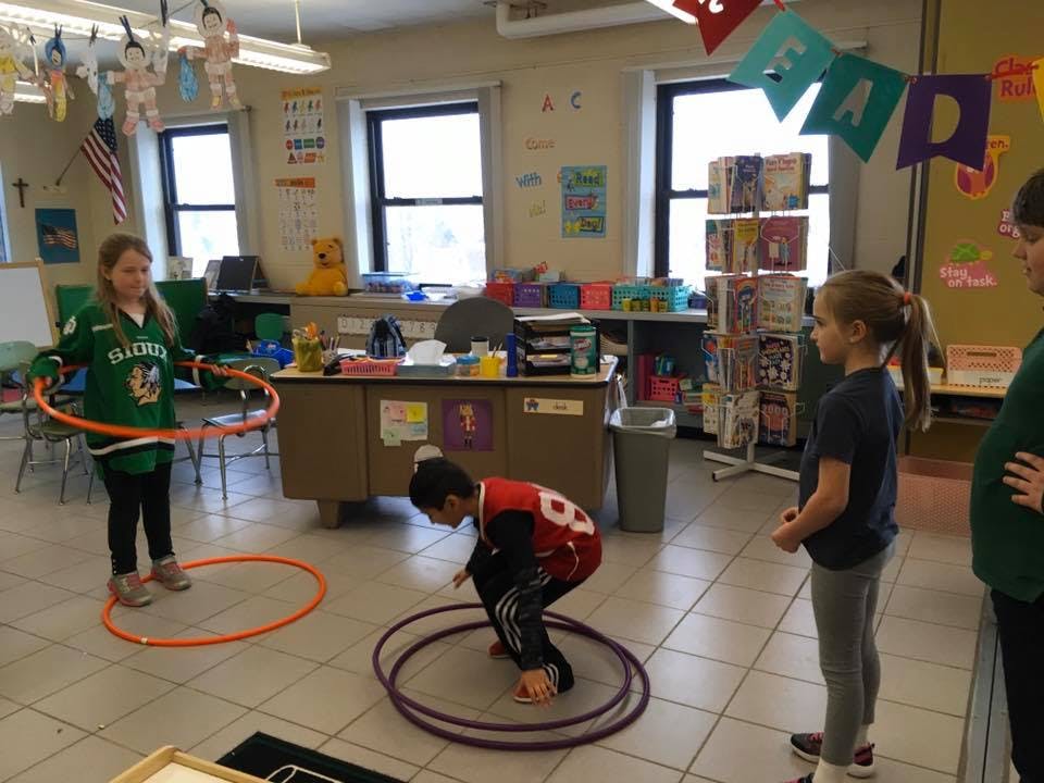 Children playing with hula hoops in a classroom