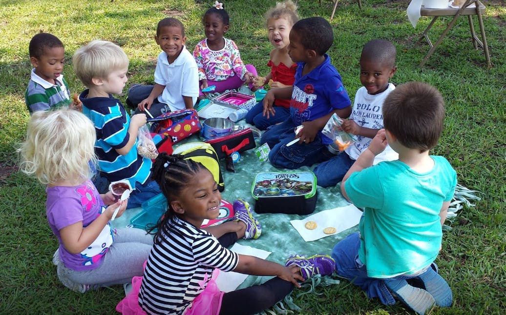 Group of children sitting on a blanket outdoors