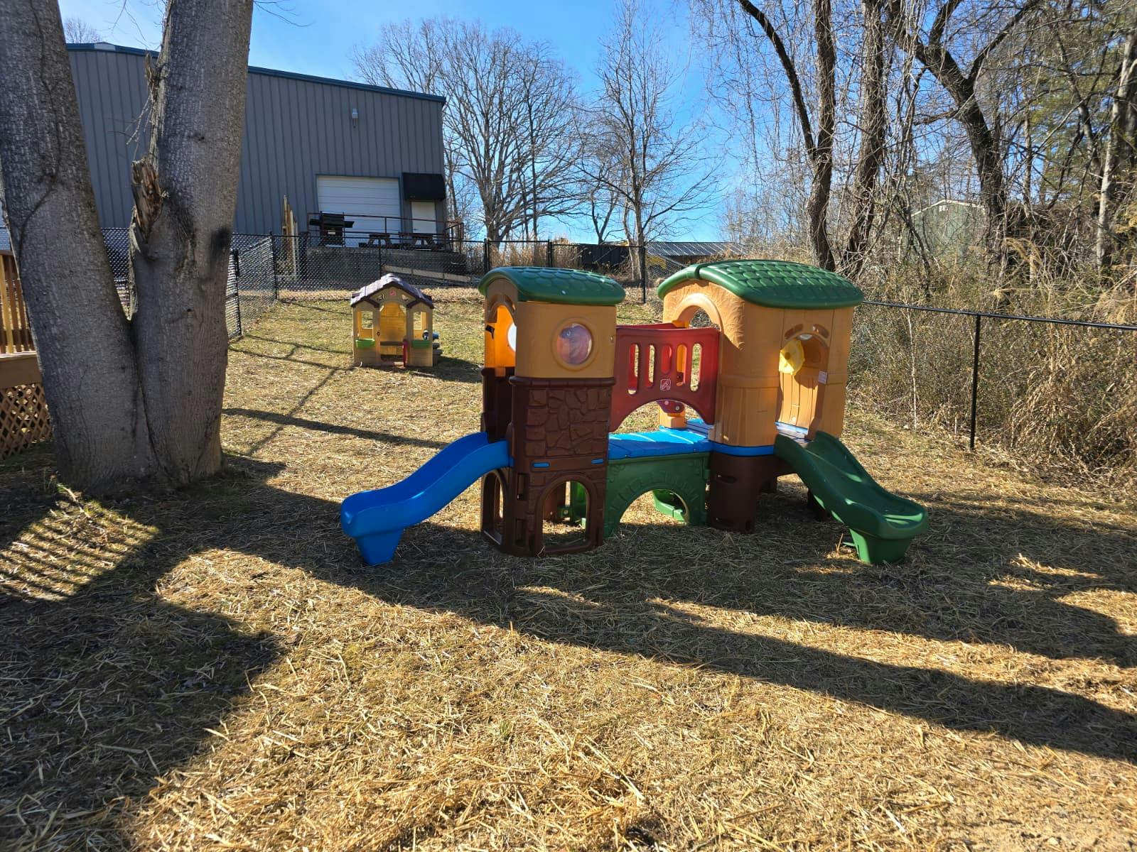 Plastic play structure with slides in a yard