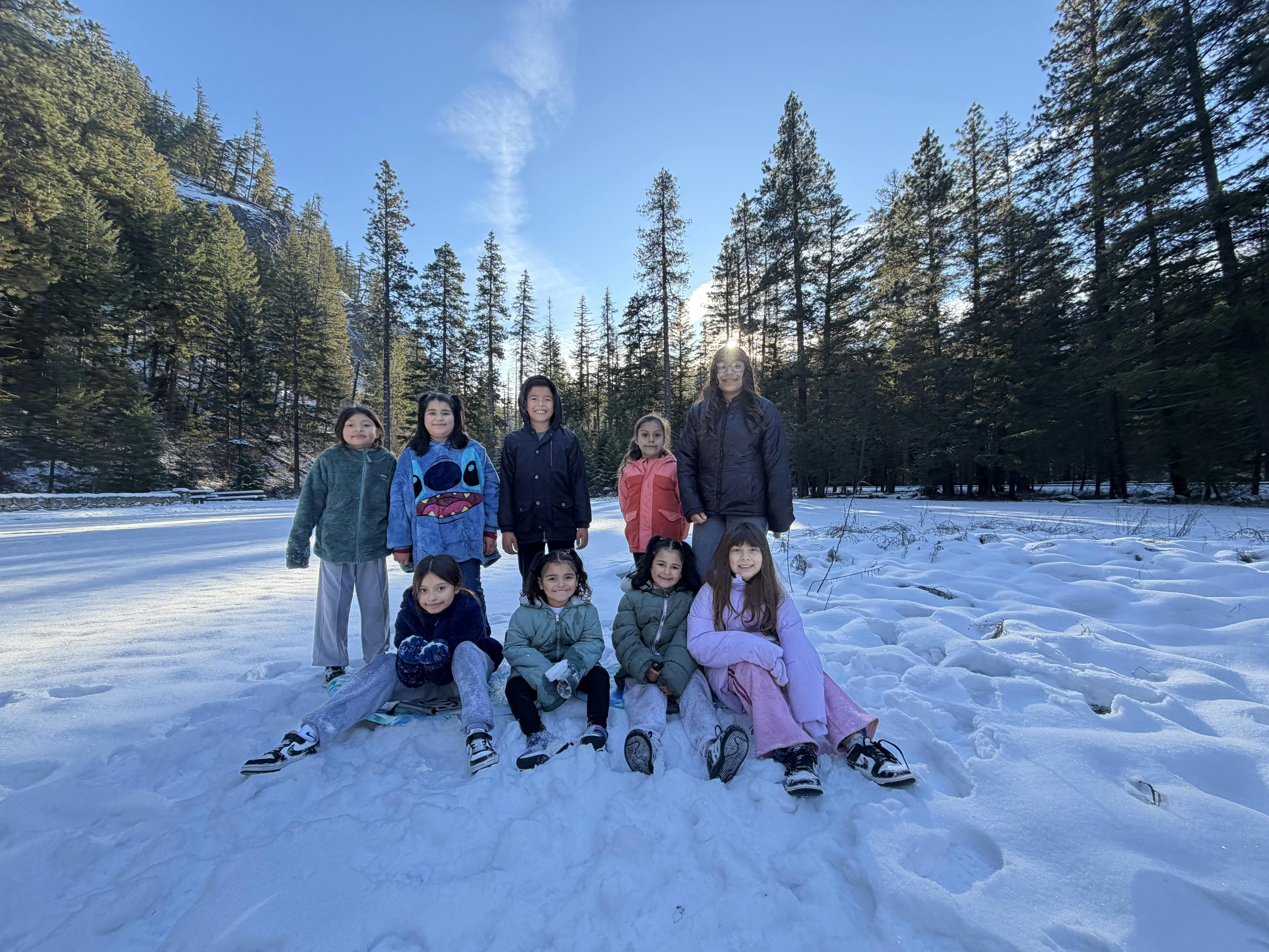 Group of children and adults posing on snow in a forest
