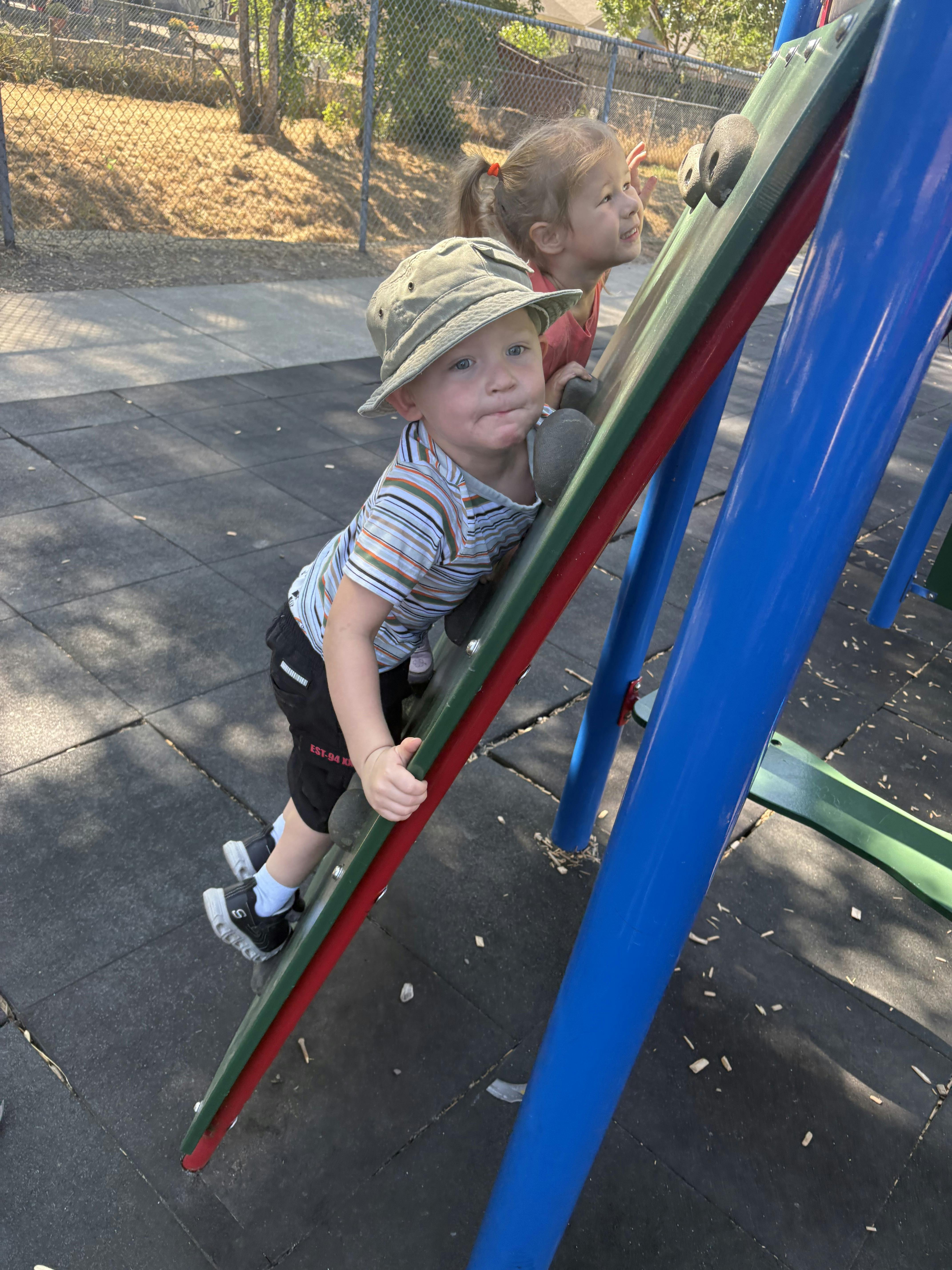 Two children climbing a playground structure