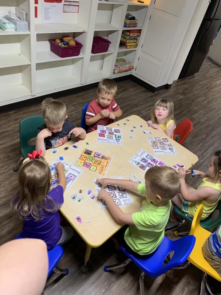 Children sitting at a table doing an activity with cards