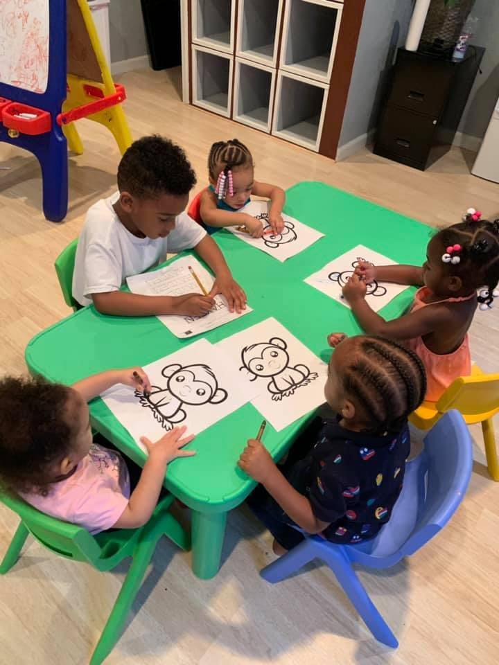 Children sitting at a table coloring monkey pictures