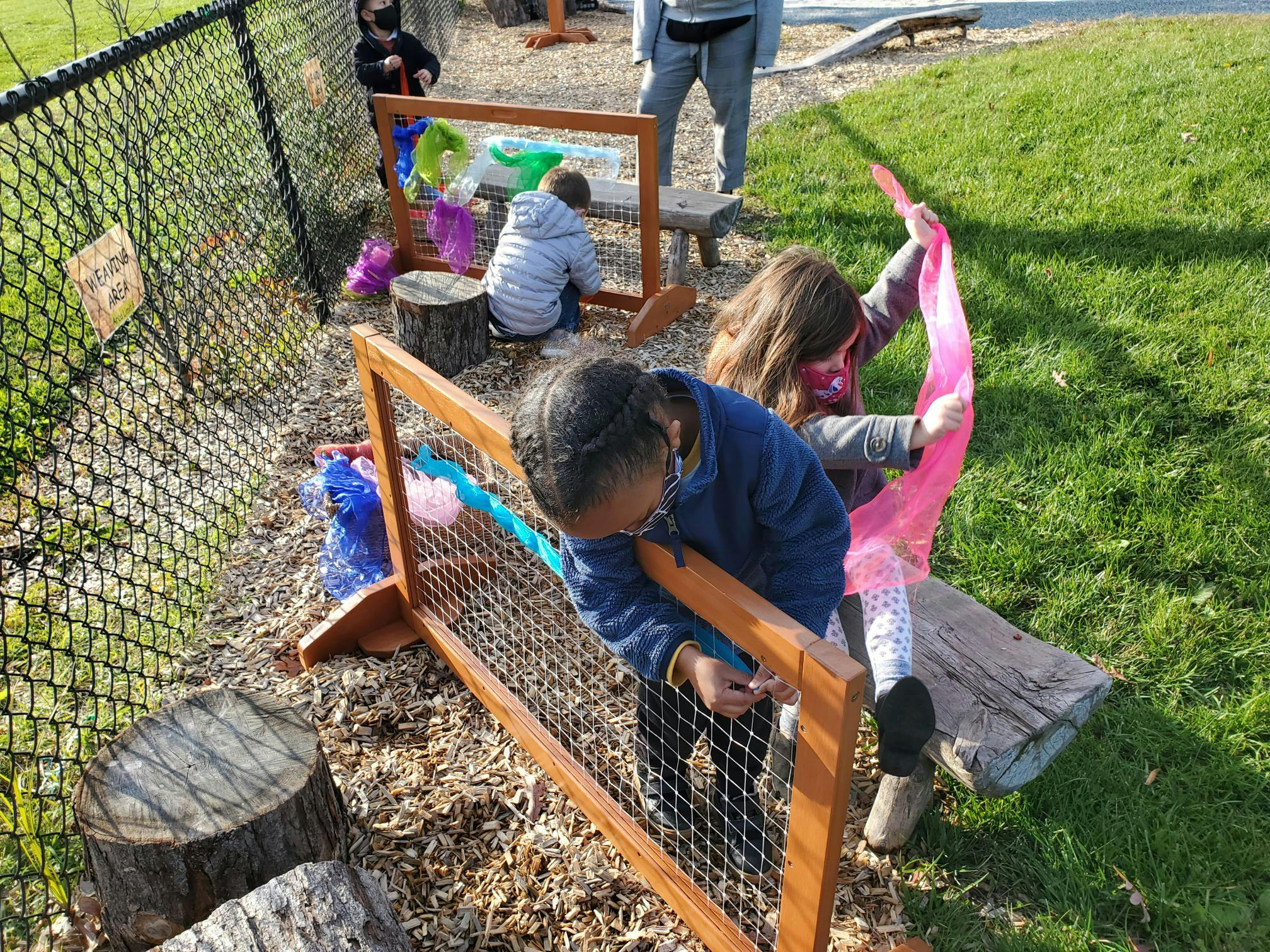 Children playing with colorful ribbons on a fence