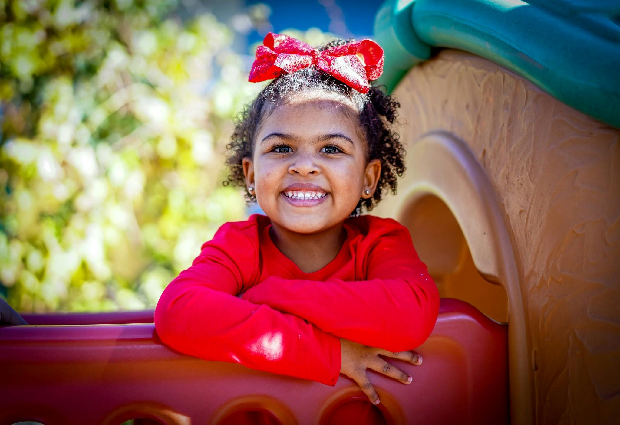 Child with a red bow in hair on a playground structure