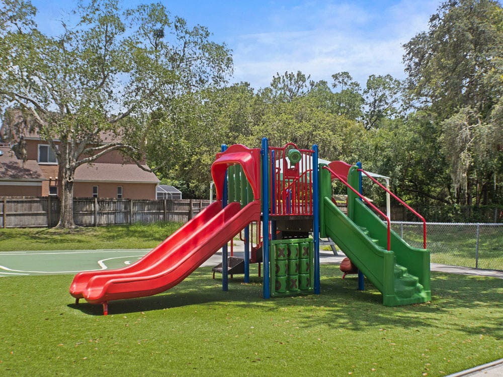 red and green playground slides with a tic-tac-toe game in a grassy area