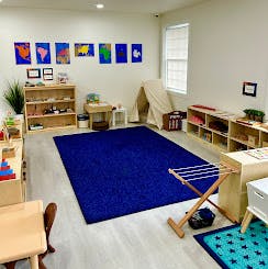 Classroom with a blue rug, shelves, and a small tent