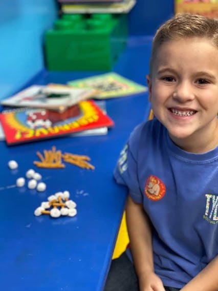 Child at a blue table with pretzels and marshmallows