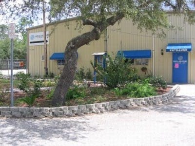Building with blue awnings and entrance sign, tree in foreground