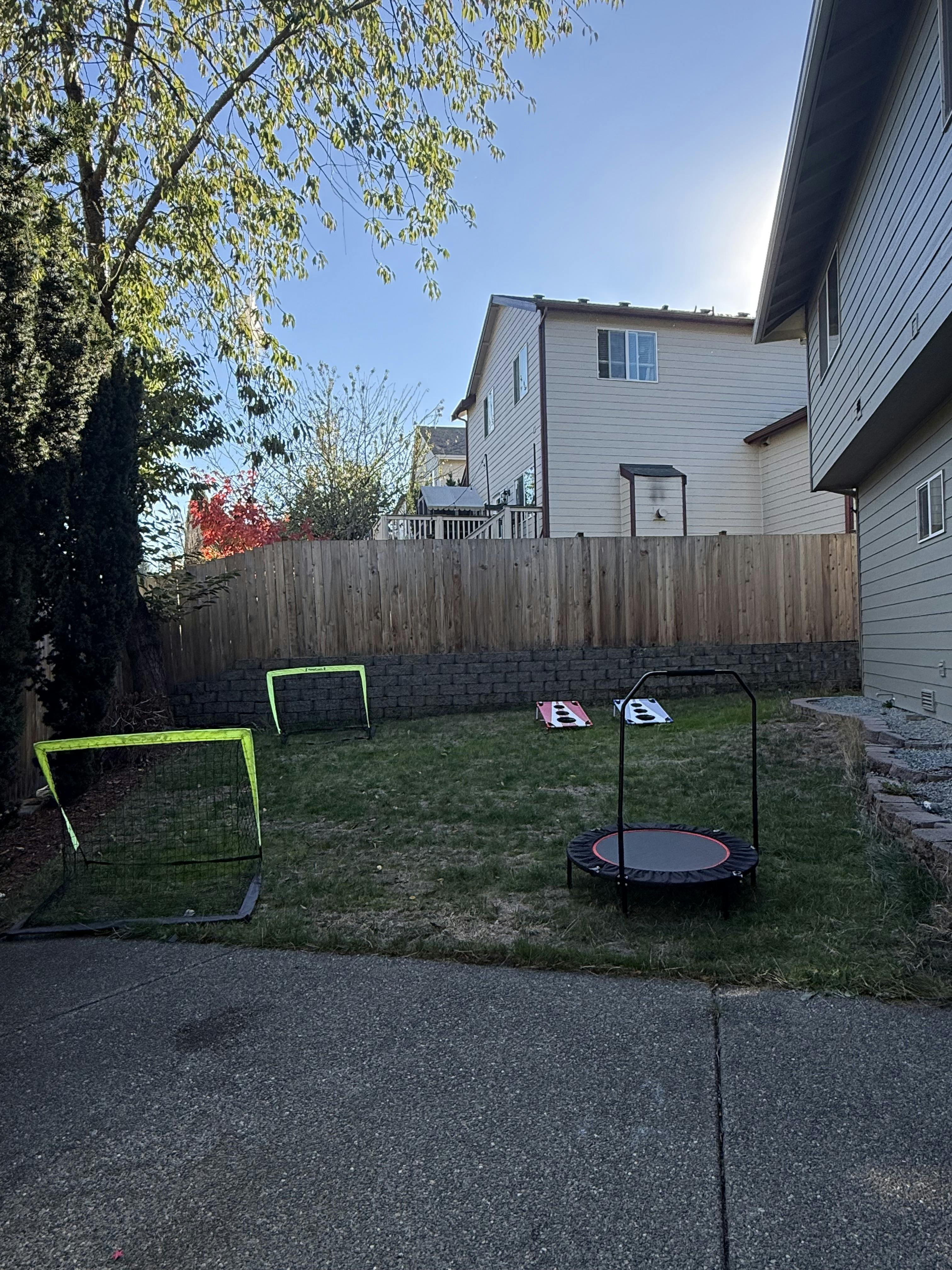 Backyard with soccer goals, cornhole boards, and a mini trampoline