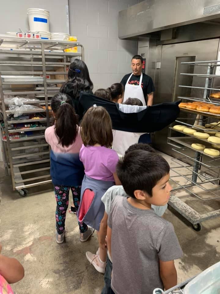 Adult in apron showing children items on baking racks