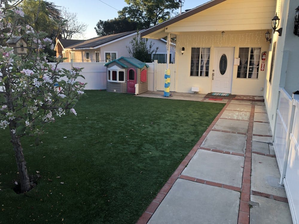 Front yard with a small playhouse and a path leading to a house