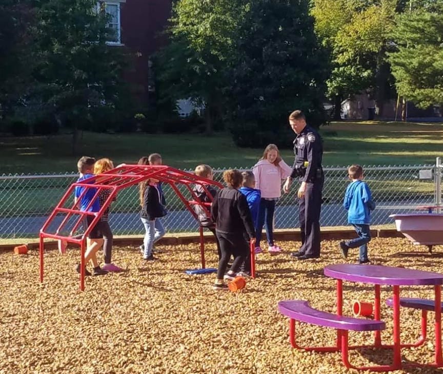 Adult in uniform interacting with children on a playground