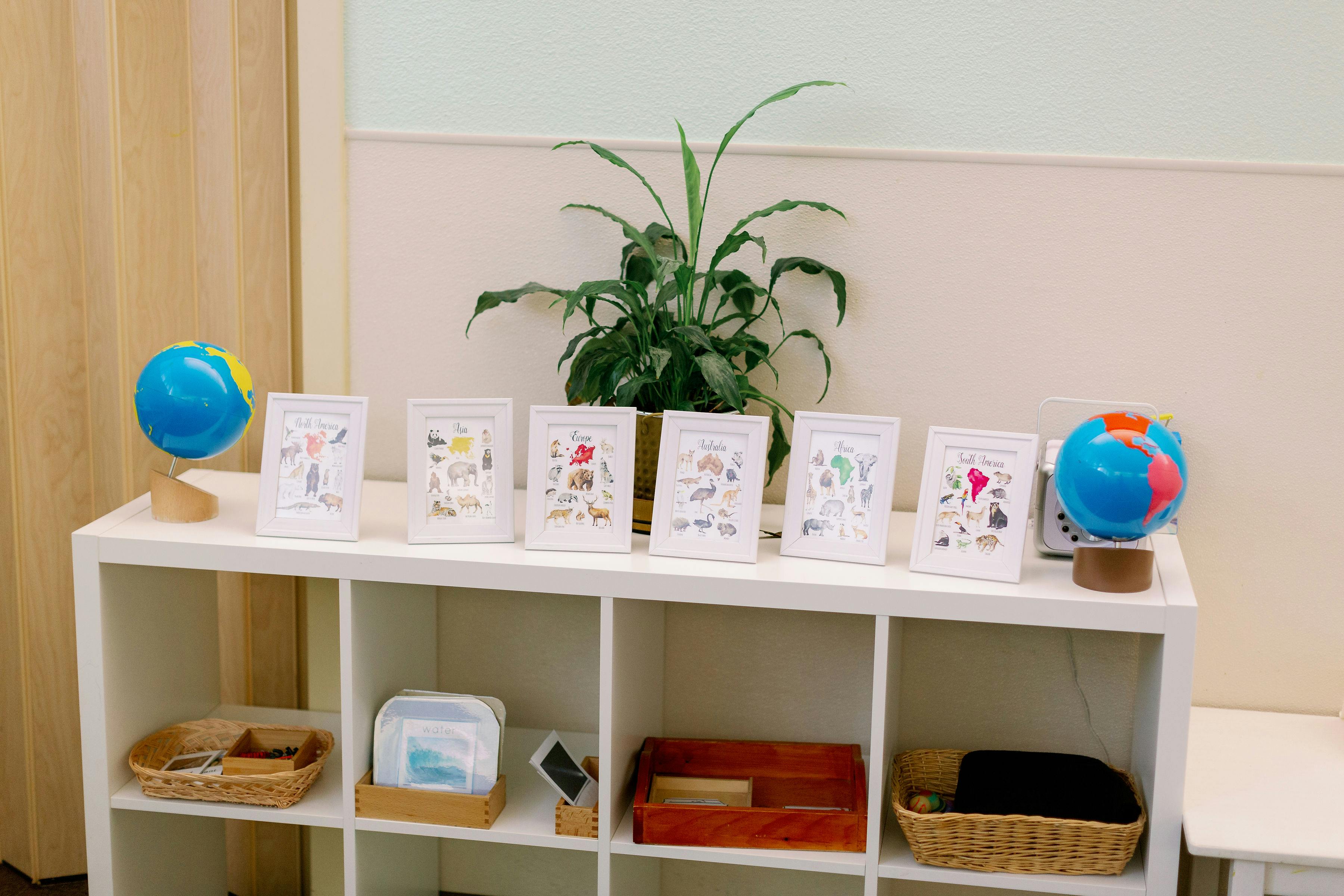 White shelf with globes, framed pictures, and baskets