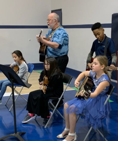 Adult and children playing guitars and violins