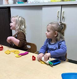 Two children at a table with playdough