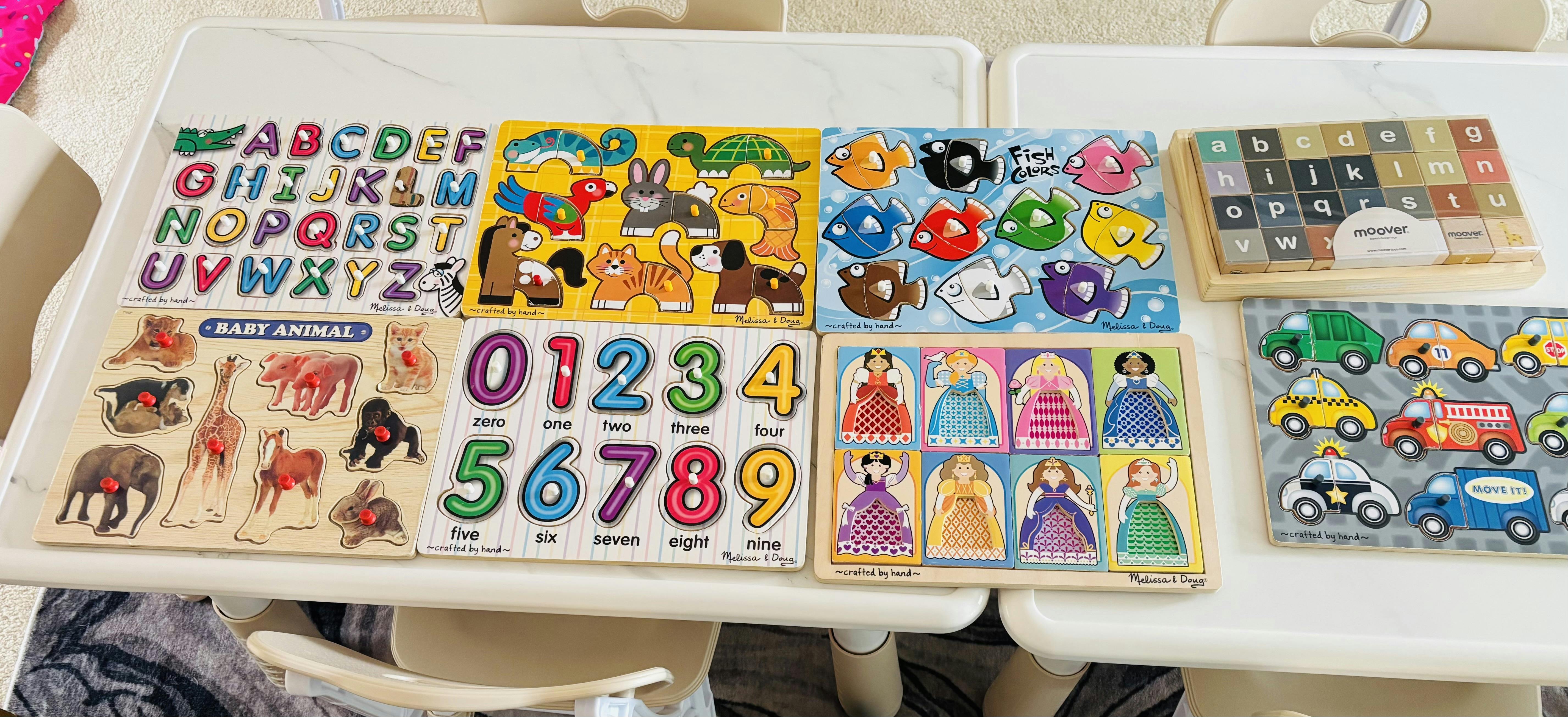 multiple wooden puzzles for children including letters, numbers, animals, fish, cars, and princesses
