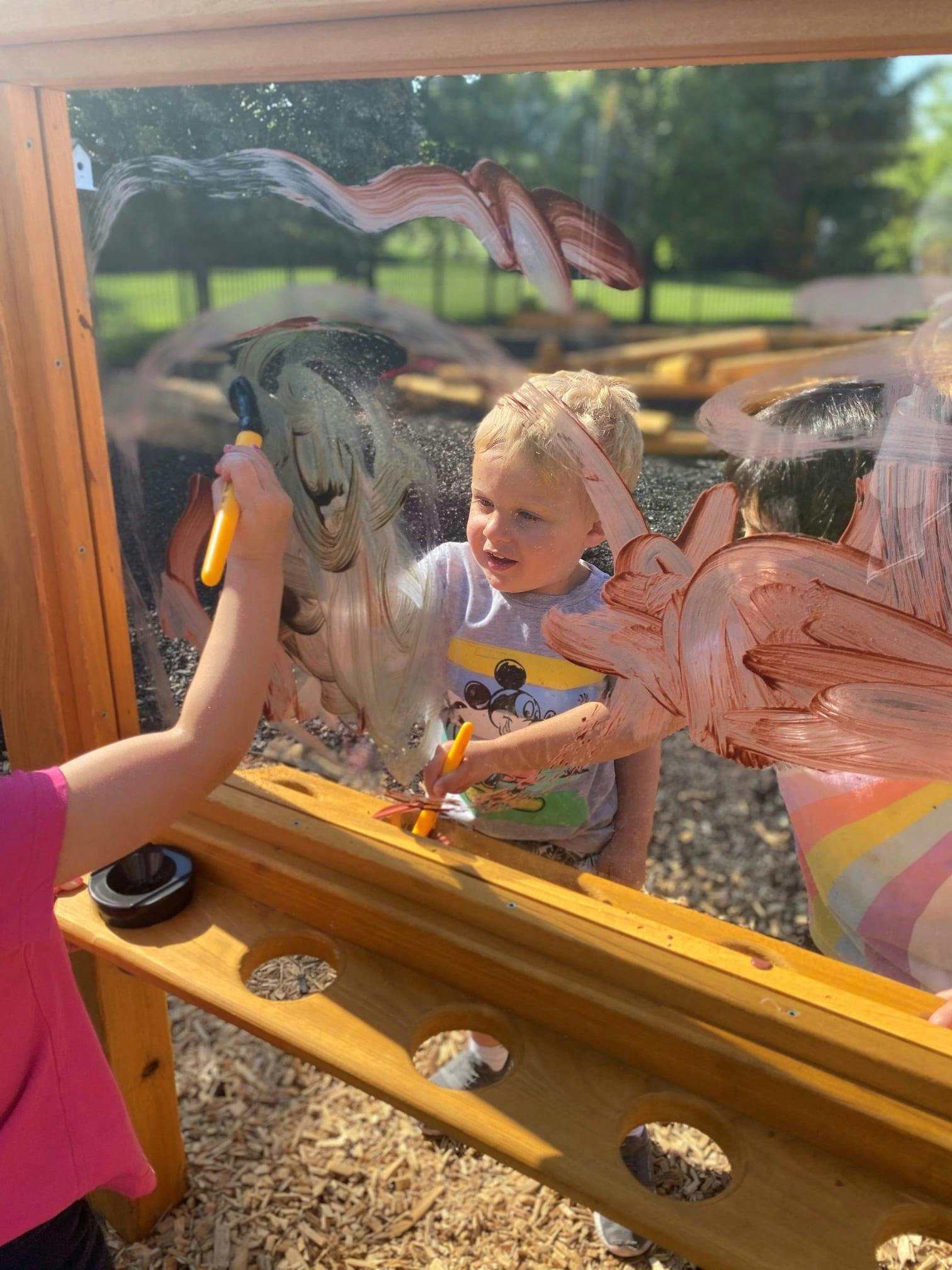 Children painting on a clear outdoor easel