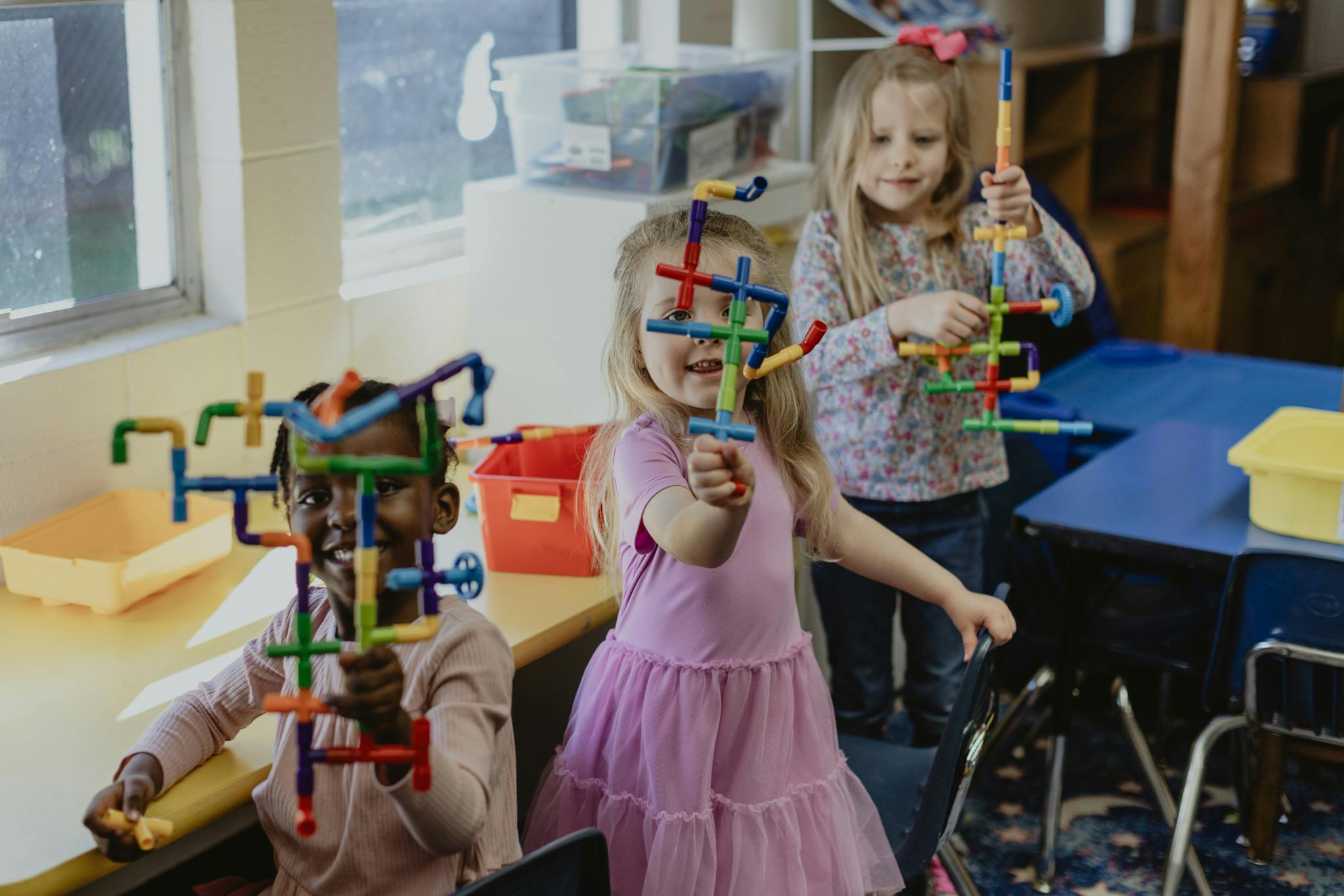 Three children playing with colorful building toys