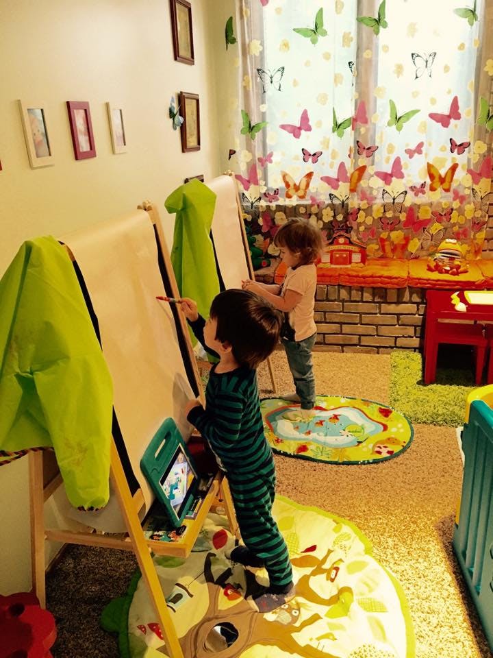 Two children drawing on easels in a playroom