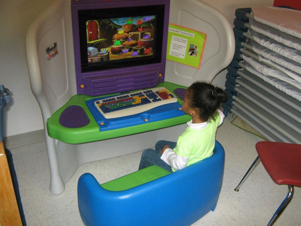 Child sitting in a chair looking at a computer screen
