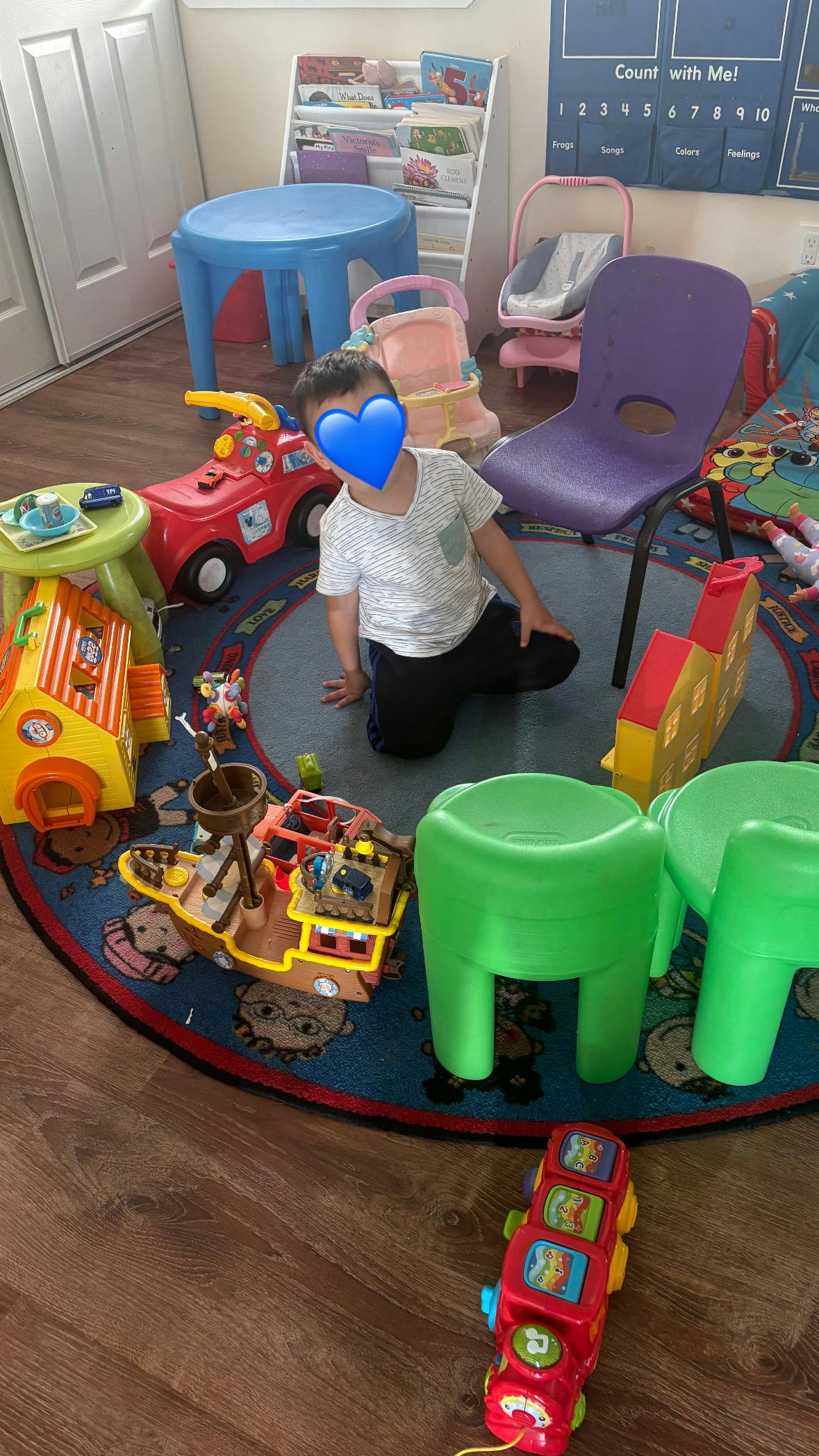 Child kneeling on a playmat surrounded by toys