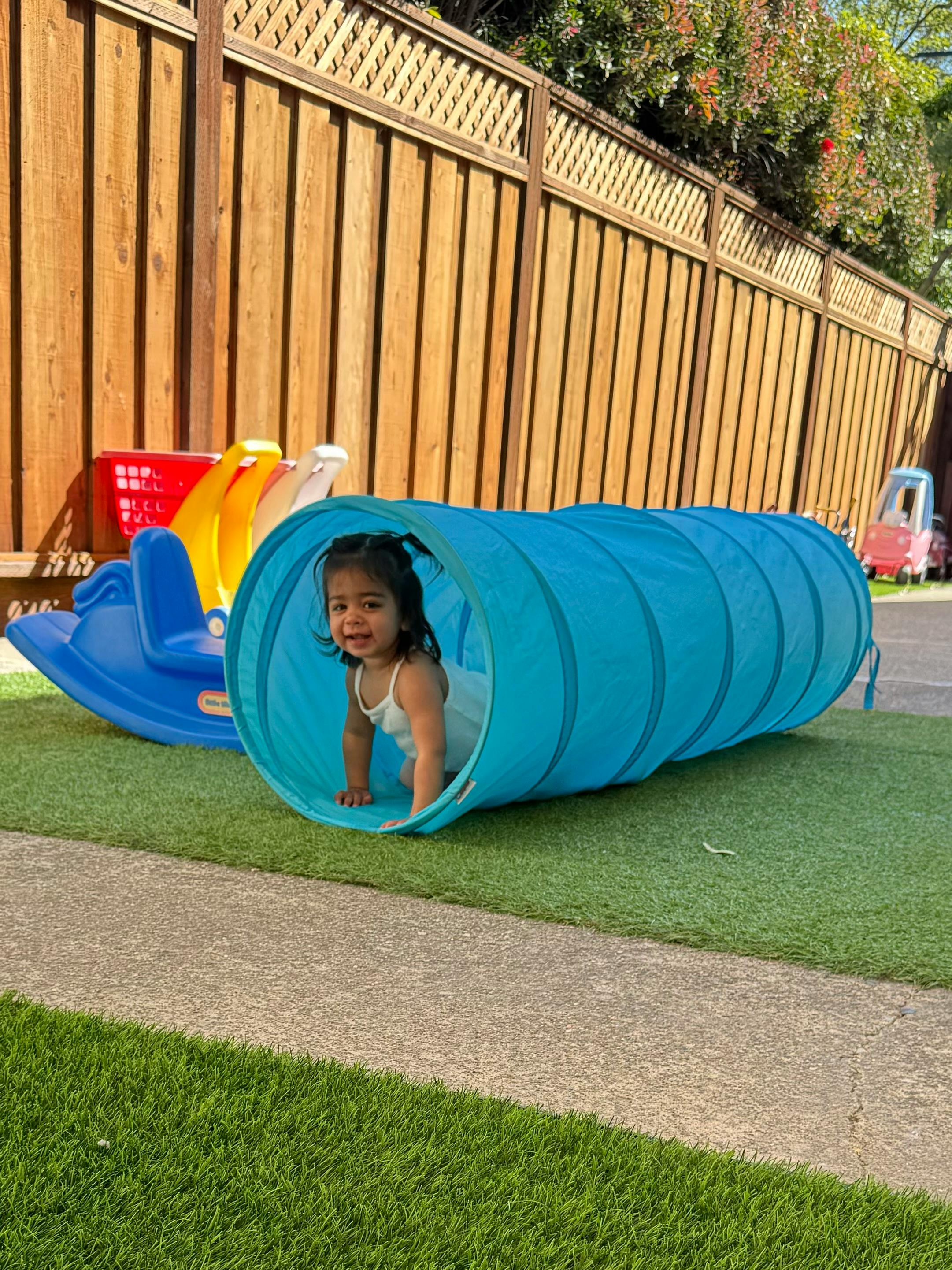 Child crawling out of a blue play tunnel
