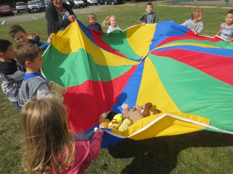 Children playing with a colorful parachute on a grassy field