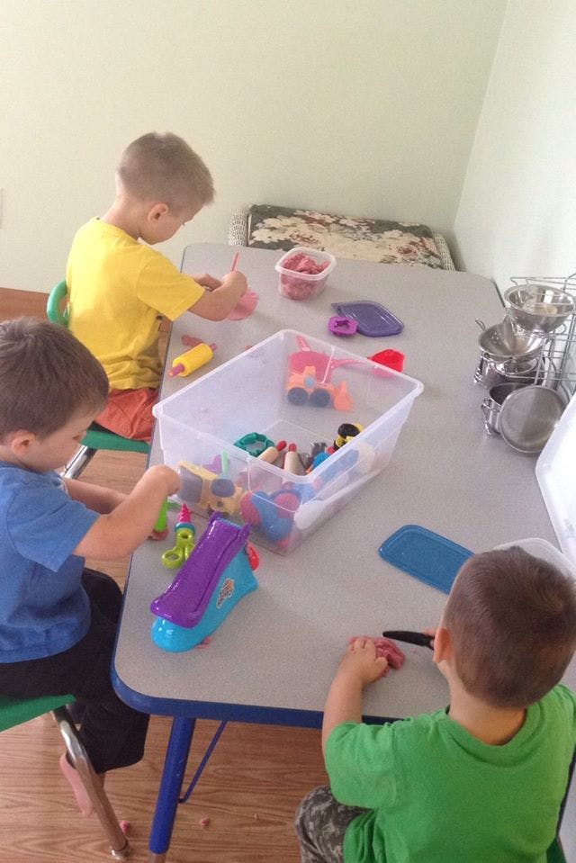 Three children playing with toys at a table