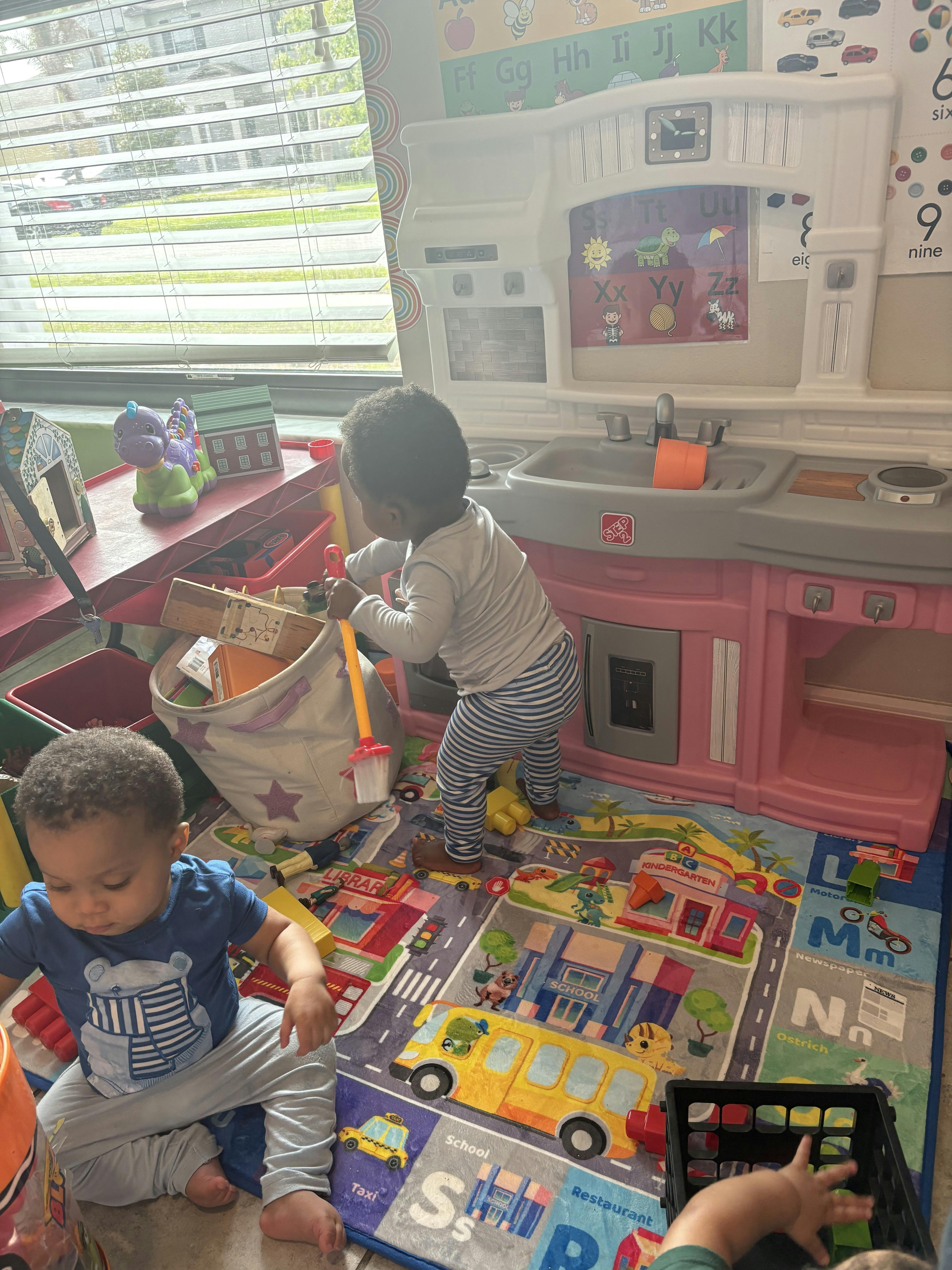 Two children playing with toys on a road map playmat