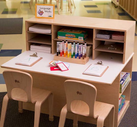 Children's desk with two chairs, markers, and clipboards