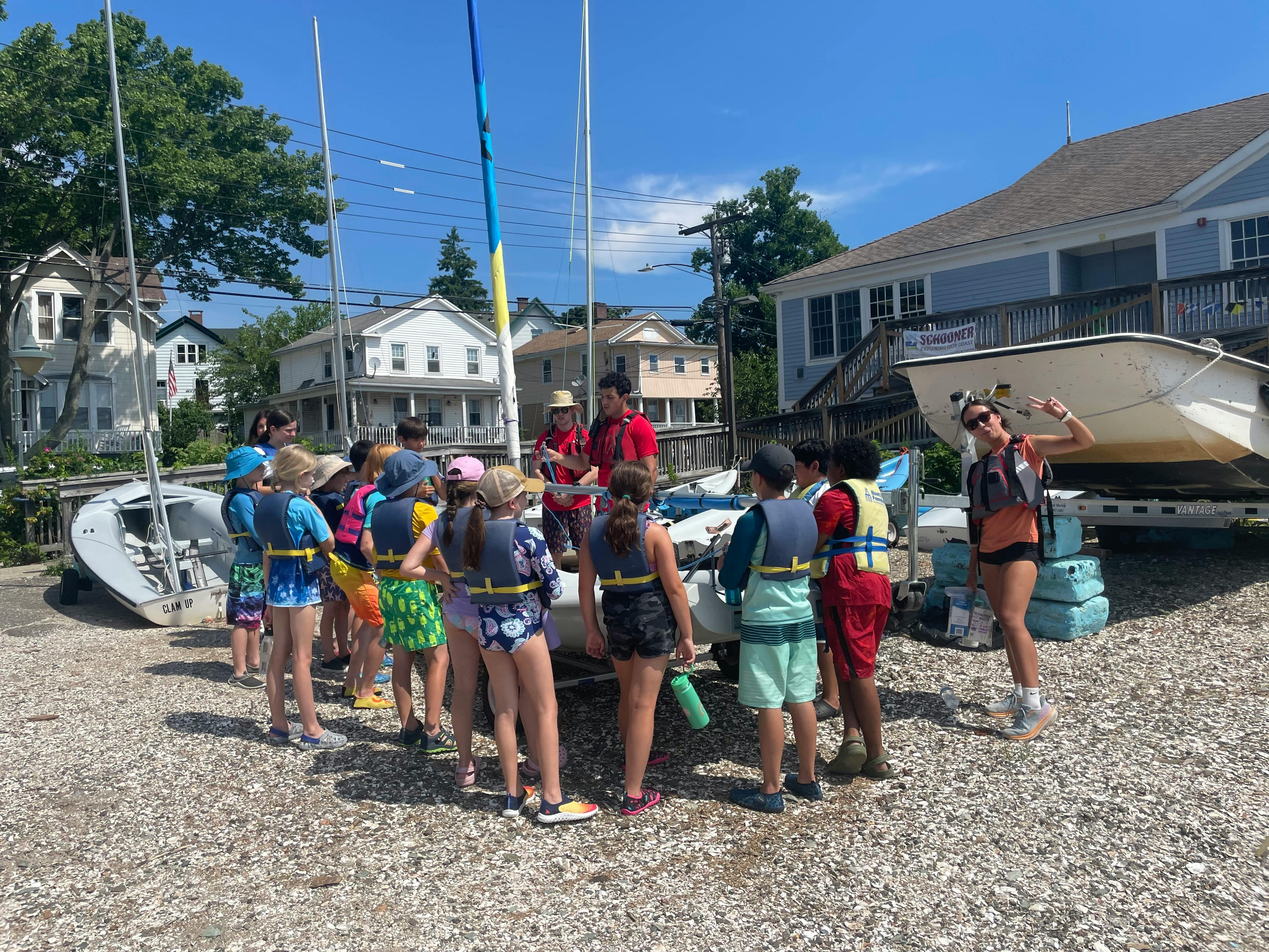 People in life vests gathered around a small boat on land