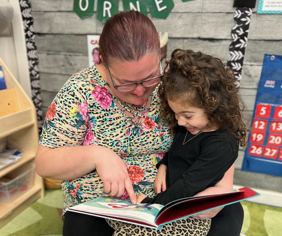 Person and child reading a book together