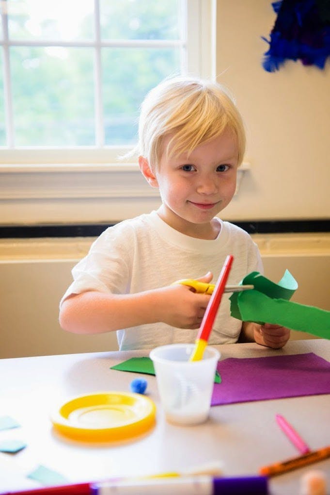 Child cutting green paper with scissors at a table