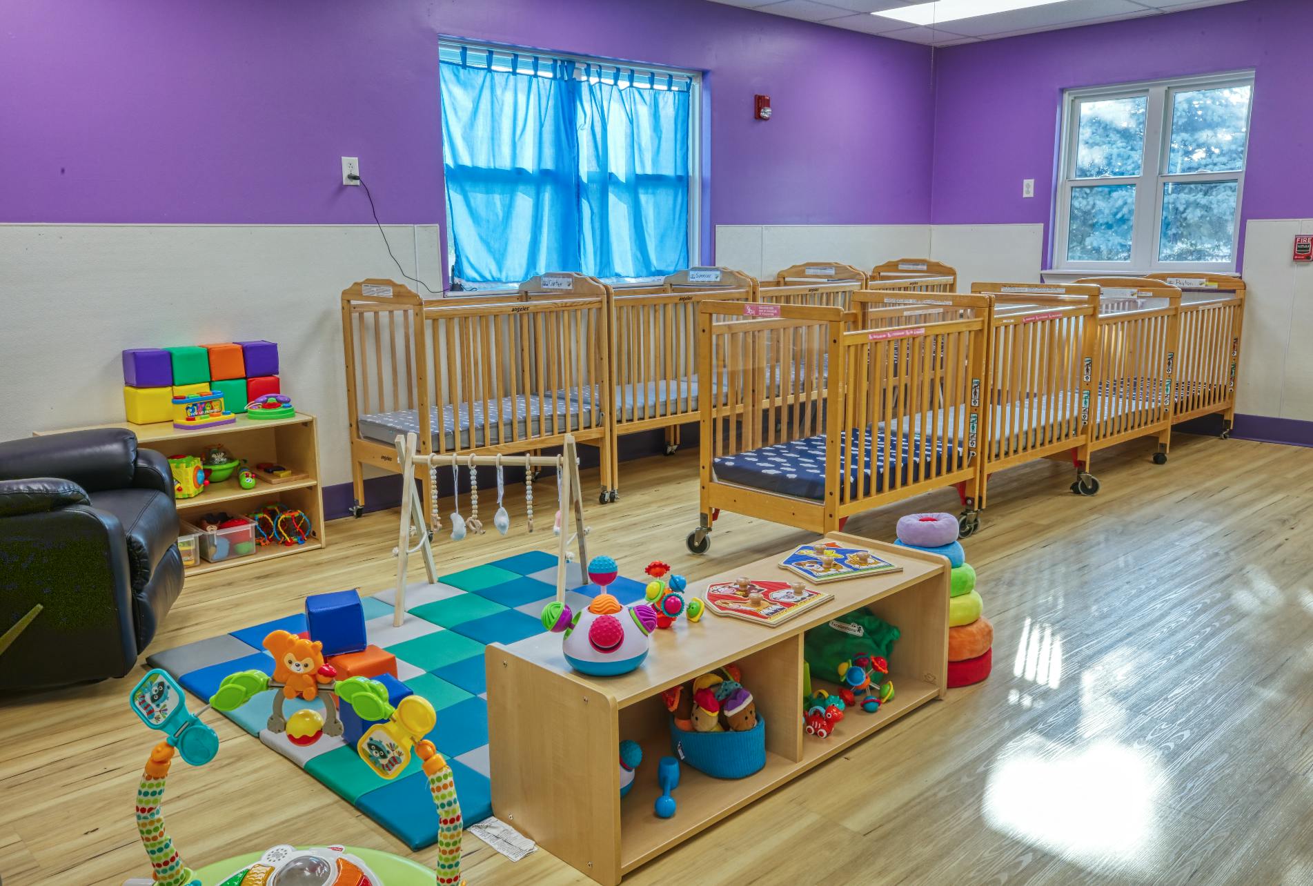 A room with multiple wooden cribs, toys, and shelves