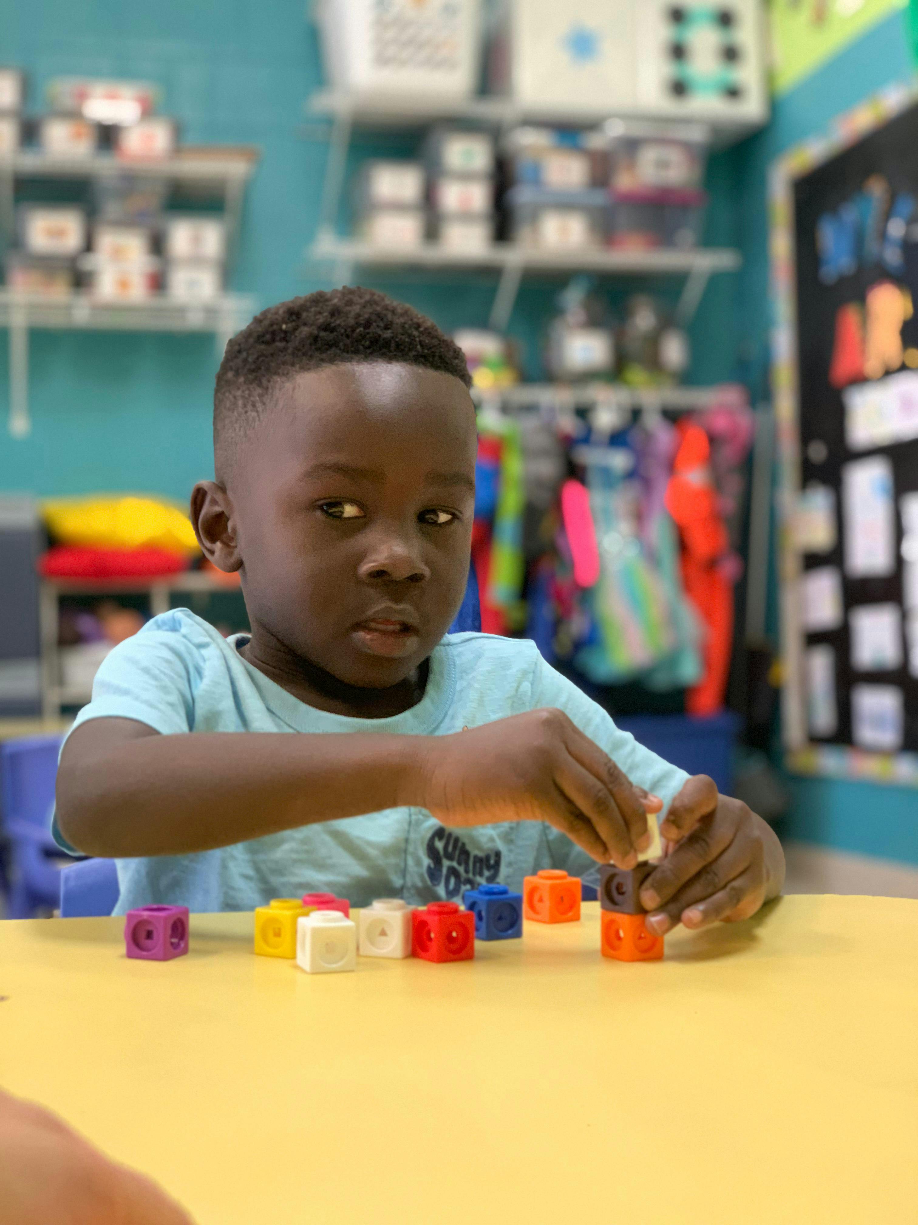 Child playing with colorful interlocking blocks at a table
