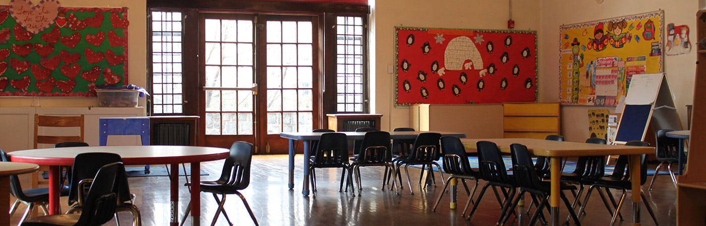 Classroom with small tables and chairs, bulletin boards, and large windows