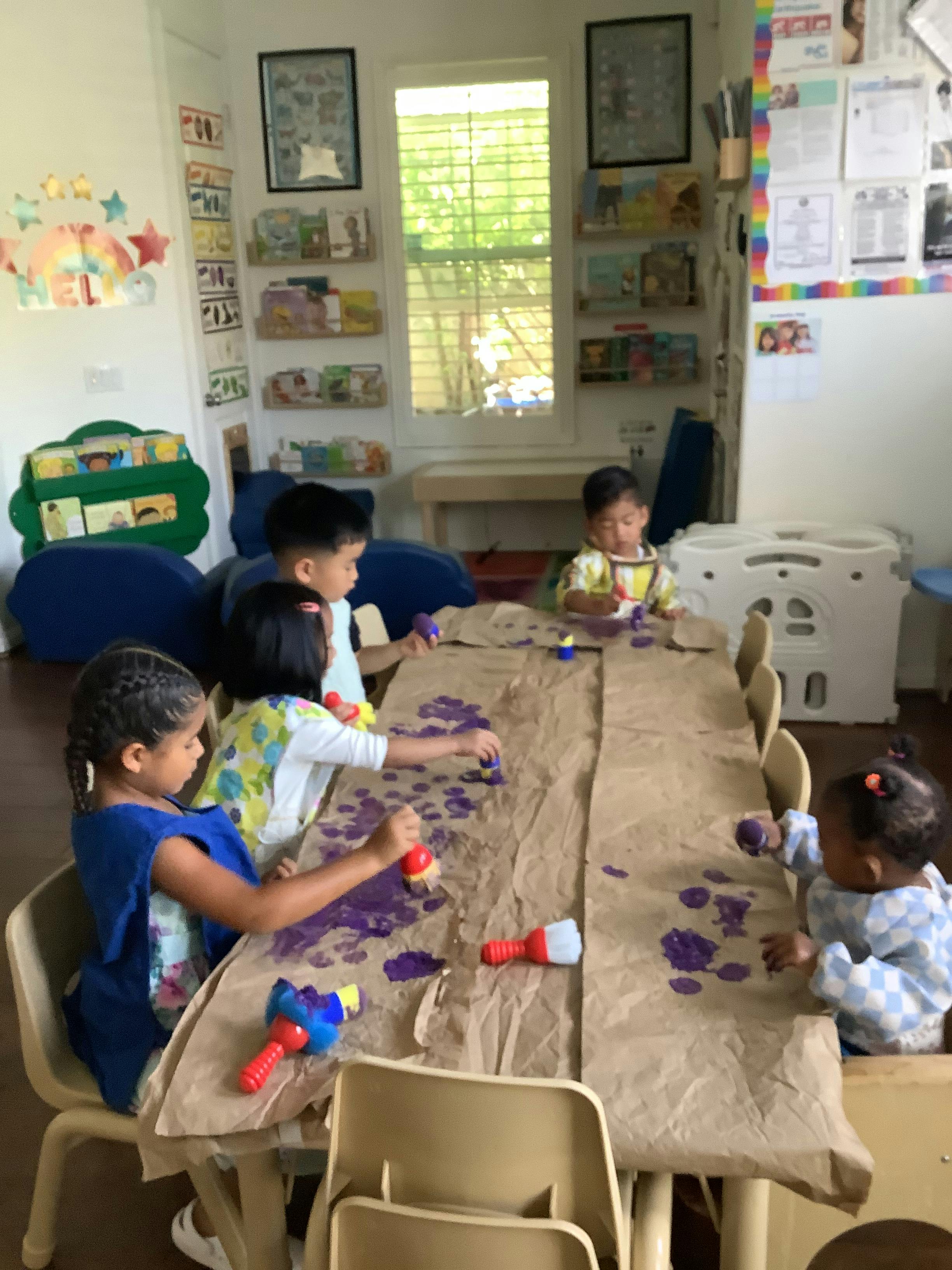 Children painting at a table in a classroom