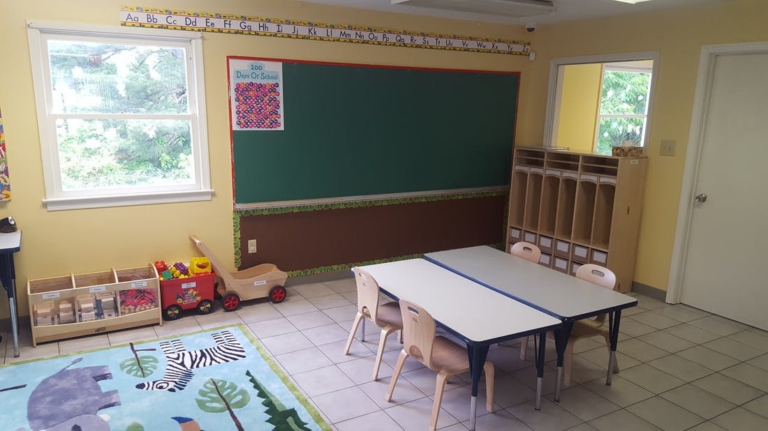 Classroom with small tables and chairs, chalkboard, and toys