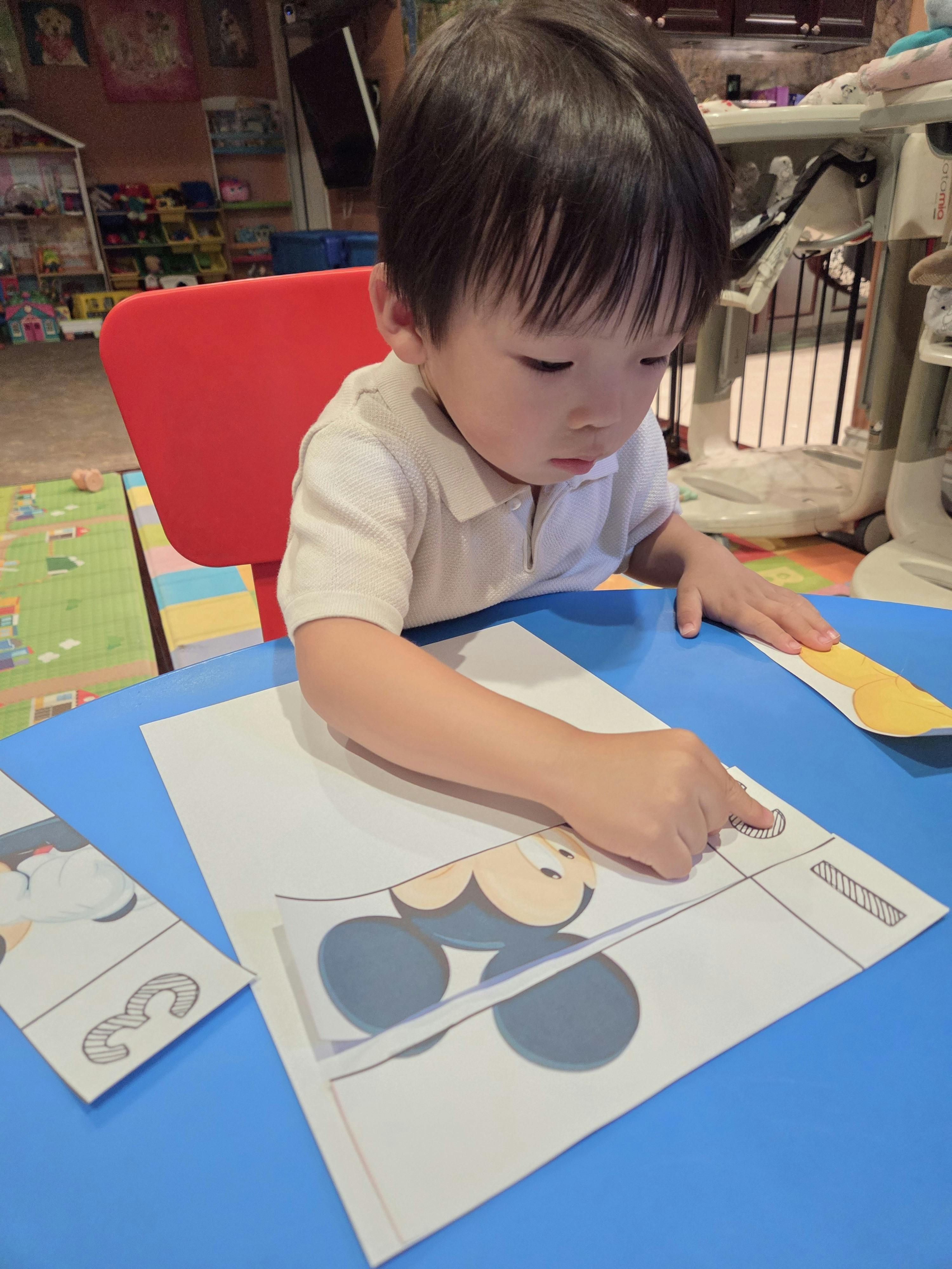 Child doing a cut-and-paste activity at a blue table