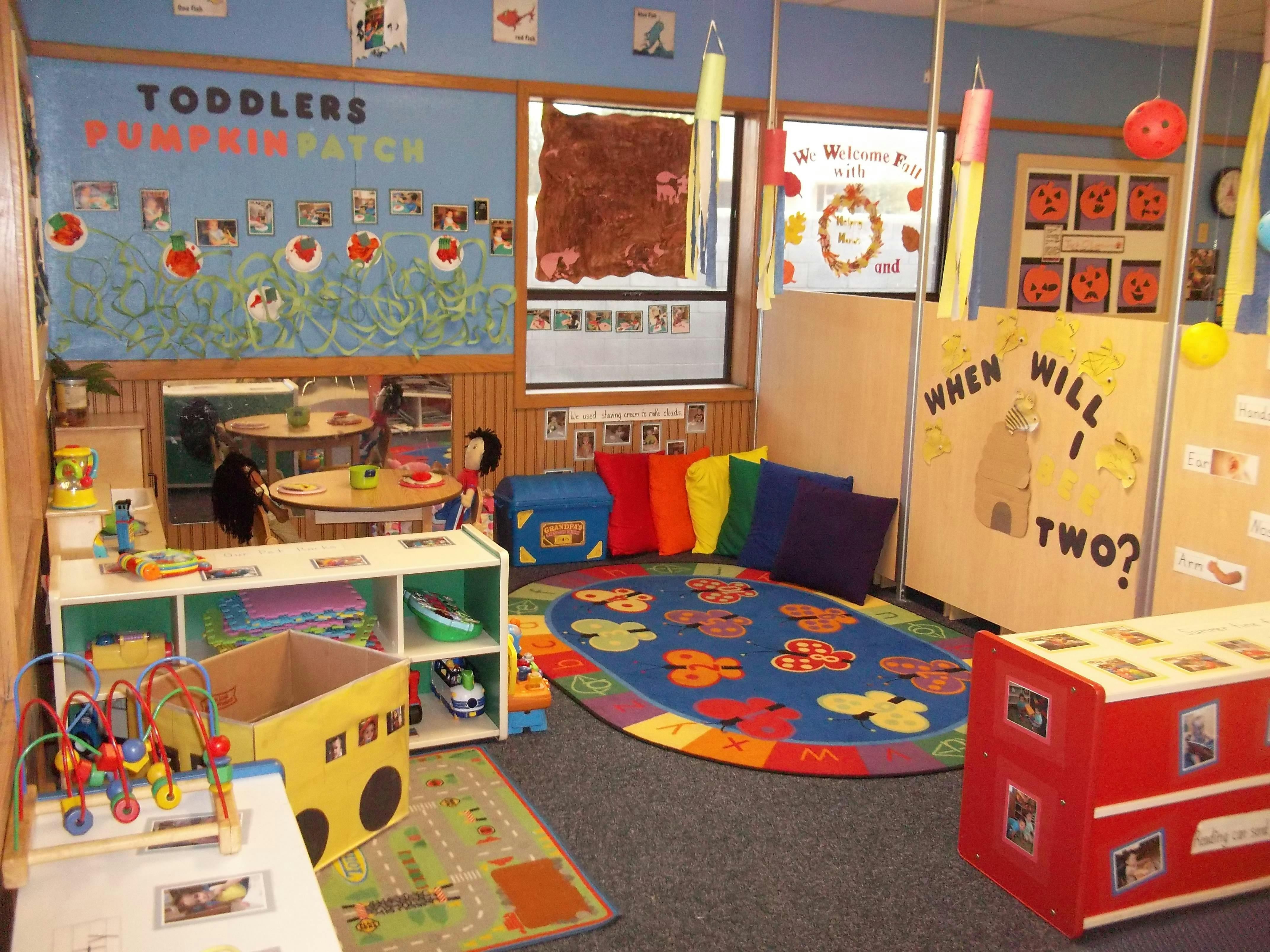 An empty classroom with posters on the walls and toys on the floor