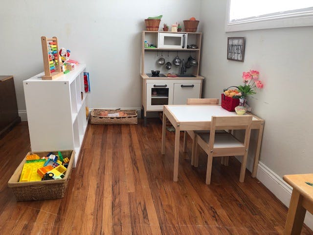 Playroom with toy kitchen, small table and chairs, and toy storage