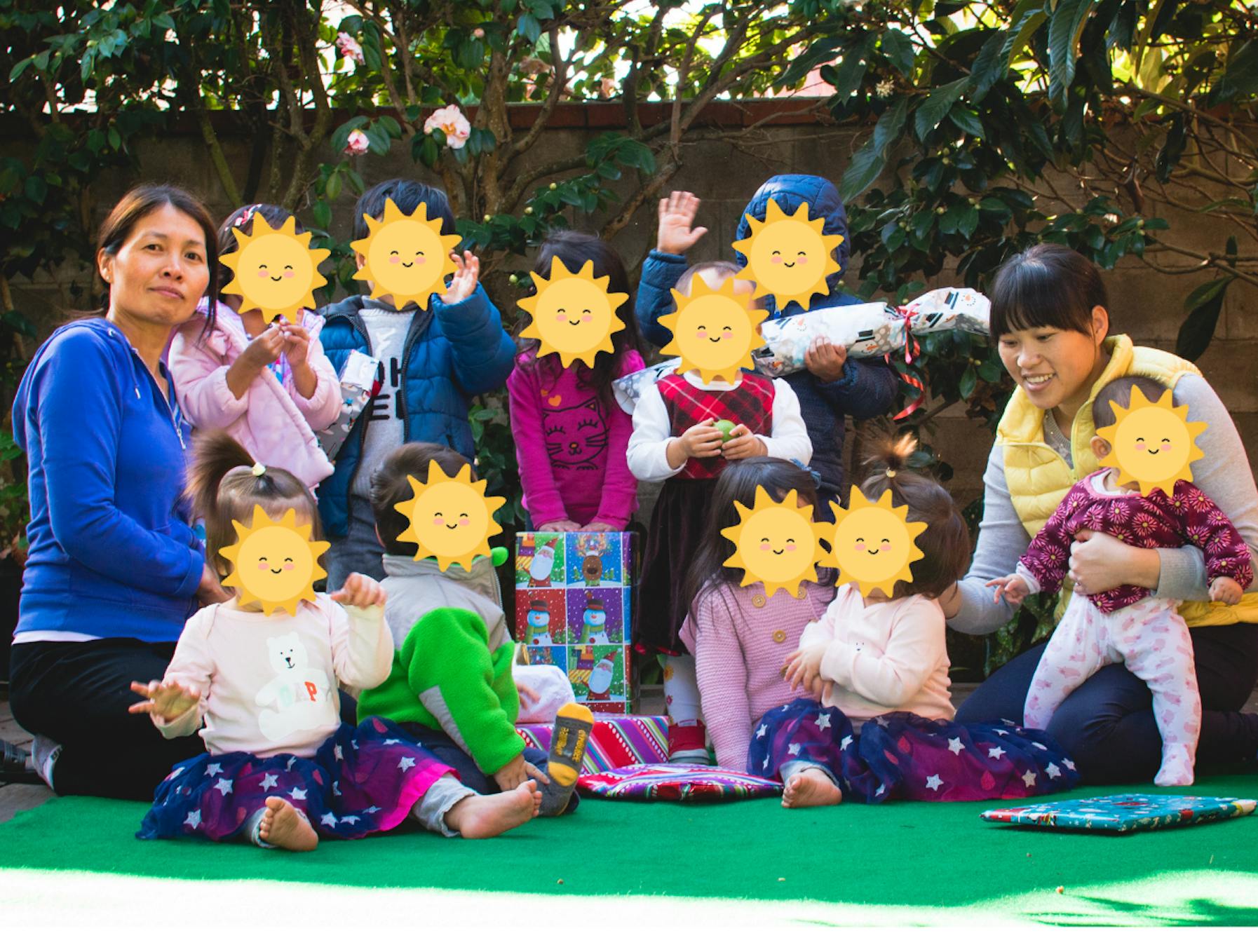 Group of children and adults sitting together outdoors with wrapped gifts