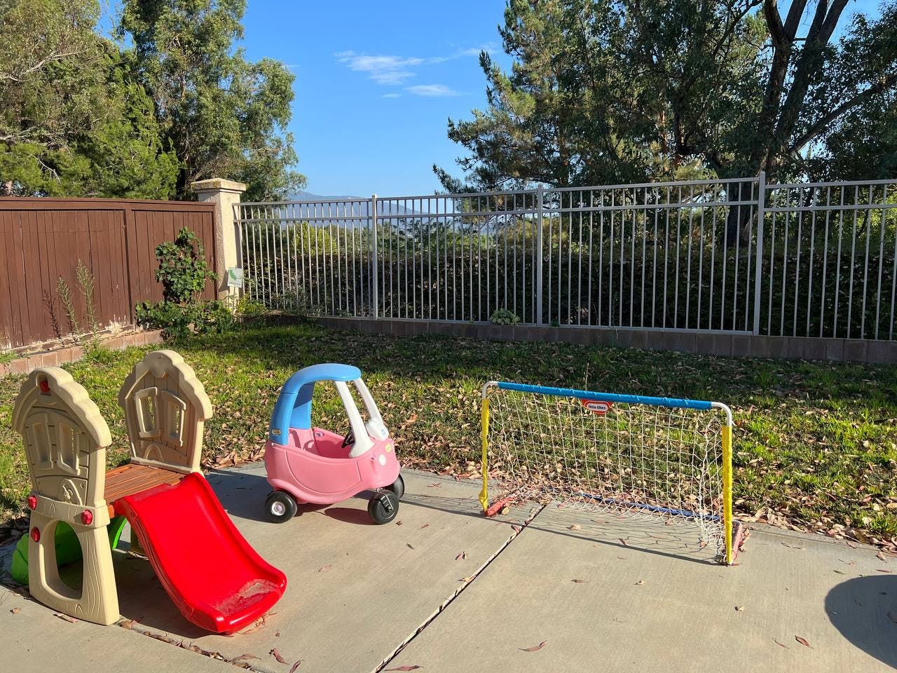 Playground slide, toy car, and soccer goal on concrete