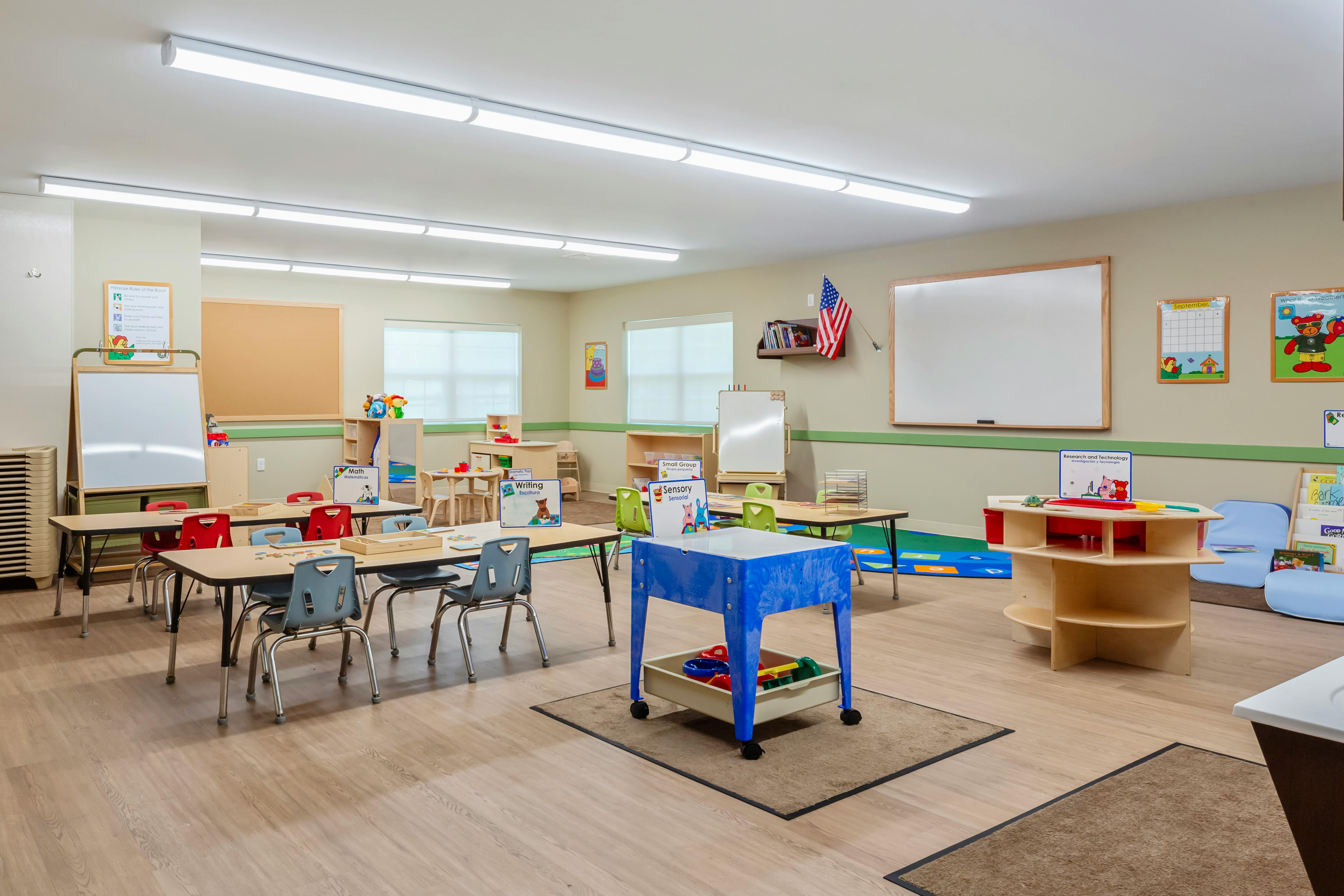 An empty early childhood classroom with small tables and chairs